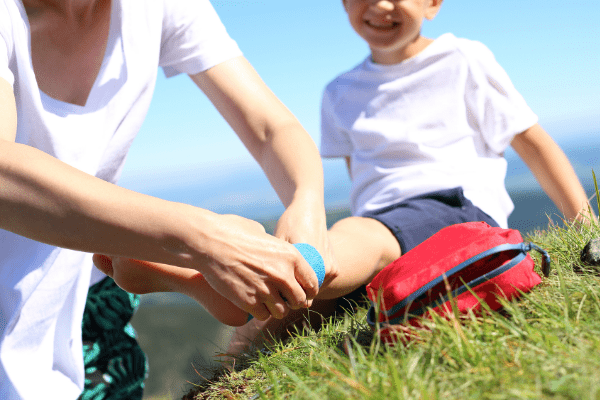 Mom bandaging her son's foot with her family travel first aid kit. 
