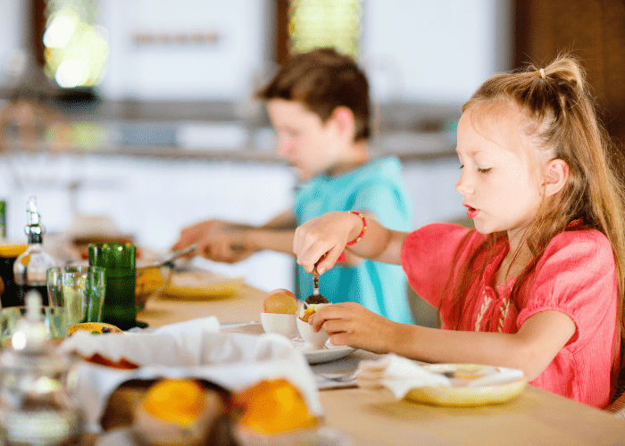 two kids eating breakfast together 