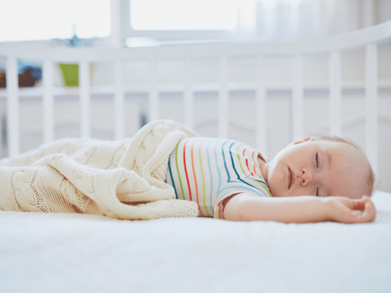 Creating a sleep schedule is a great way to get things done with a baby - this picture is of a baby sleeping in their crib. 
